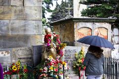 A woman holding an umbrella stands in front of a grave at a cemetery in Bogotá, Colombia