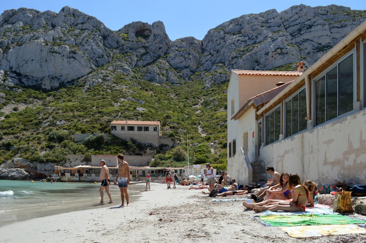 Panoramic view of Calanque de Sormiou main beach with turquoise water and rocky cliffs