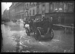 Flooded street in the 15th arrondissement of Paris during the January 1910 floods, people crowded on a cart in Rue du Théâtre near Rue Saint-Charles