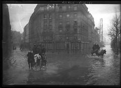 Horse-drawn carts moving through flooded streets at Place Saint-Charles in Paris during the 1910 floods