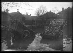 Flooded street in Paris with two carts carrying debris on Rue de la Convention
