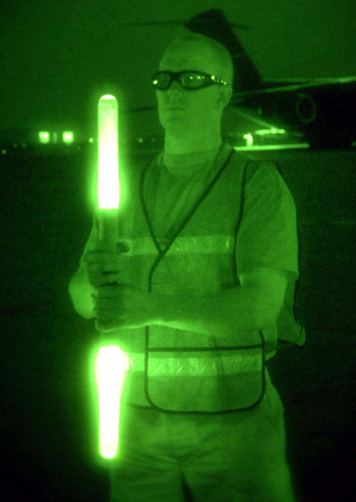 Staff Sgt. Jacob Whetstone signaling with marshalling sticks to UH-60 Blackhawk helicopters at Baghdad International Airport
