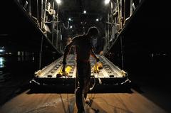 Senior Master Sgt. Archie Brawton placing chalks under C-130 Hercules aircraft at Baghdad International Airport