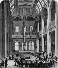 Sunny South Hall on the second floor of Astor Library with wooden bookshelves and seating