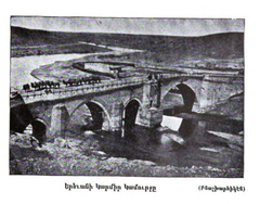 Red Bridge in Yerevan over a river with cityscape in the background