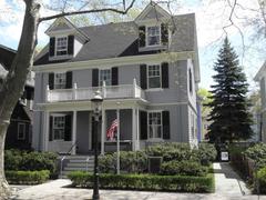 Two story gray house with two dormers in roof at John F. Kennedy National Historic Site with flag flying and gas lamp on sidewalk in spring