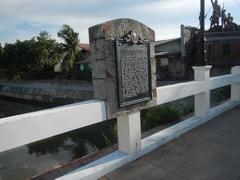 Alabang-Zapote Road in Las Piñas City showing commercial buildings, Zapote bridges, historical markers and city landmarks under a clear sky