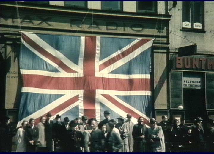After May 5th 1945 liberation scene at Nytorv Copenhagen with Climax radio store decorated with huge British flag and bystanders watching courthouse