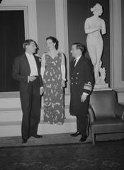 Lady in long dress singing between naval officer and tuxedo man in The Land of Smiles operetta
