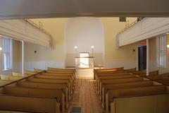 Interior of the African Meeting House with wooden white pulpit and yellow wooden benches along the aisle