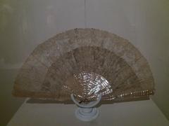 Antique lace fan with intricate needle lace, Brussels stitch, burgau mother-of-pearl handle, and copper ring from early 1900s Belgium or France