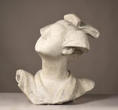 Sculpture of a person with lifted head, fine features, slanted eyes, hair pulled back with ribbons