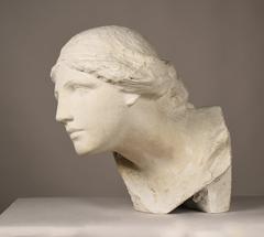 Sculpture bust of a person with an oval face and abundant hair tied with a ribbon