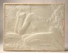 Nude woman kneeling in profile, leaning on a basin, holding her face with both hands, with vines on the right