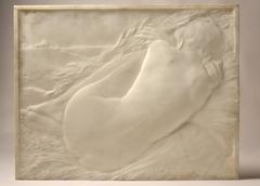 Nude woman lying on wheat sheaves viewed from behind with haystacks in the distance