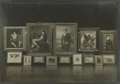 Two rows of paintings of various sizes displayed on easels in Galerie Henry Vasnier