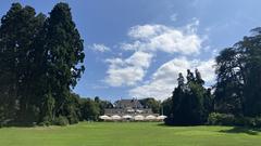 Park landscape with manicured lawns and trees under a clear blue sky at Parc des Eaux-Vives