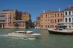 Water taxi and vaporetto on the Canal Grande at Rio di San Polo intersection in Venice with historic palazzos in background