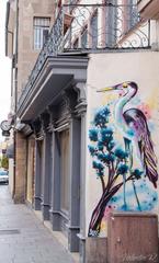 Heron perched along a wall at the exit of Place Gutenberg, watchful for fish remnants near the site of old fish markets