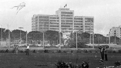 Children and youth flying kites in Campo de Marte during winter in Lima with the Ministry of Labor building in the foreground
