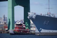 USS New Jersey battleship being moved down Delaware River by tugboats