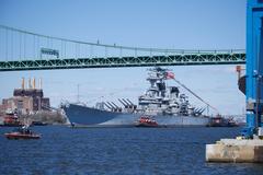 Battleship USS New Jersey being moved by tugboats down Delaware River for maintenance