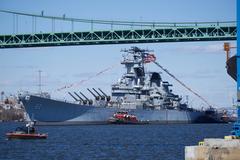 Battleship USS New Jersey being moved by tugboats down Delaware River