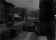 Historic view of Sherbrooke Street near McGill University in Montreal with colonnaded portico in background, shops and horse-drawn car and car on street