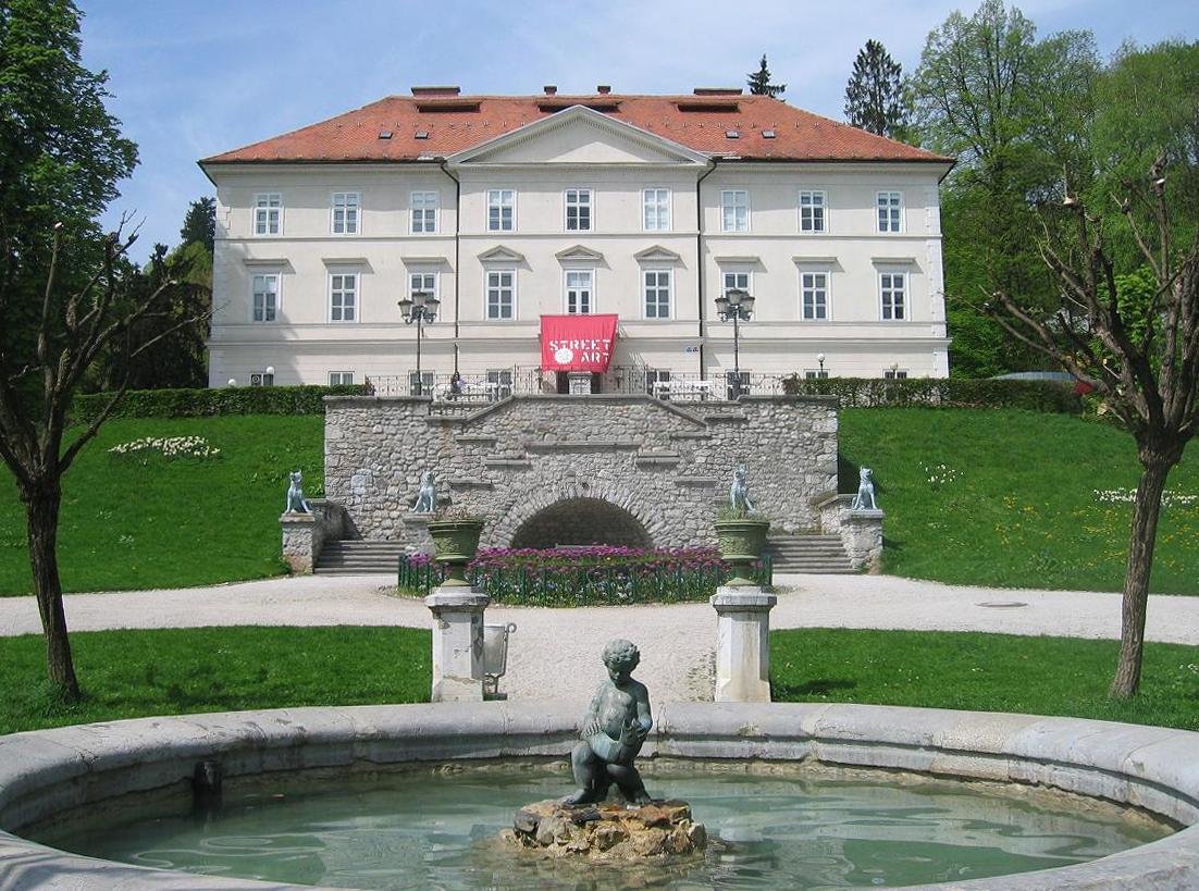 Boy with a Fish sculpture and four dogs statues at Tivoli City Park in Ljubljana with Tivoli Castle in the background