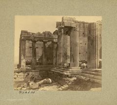Western facade of the Propylaea showing the Pinacotheca and Doric columns with stone tables holding sculpture fragments on the Acropolis