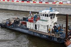 BTM-302 tugboat moored under Bolshoy Kamenny Bridge in Moscow during bridge repairs with construction waste barge