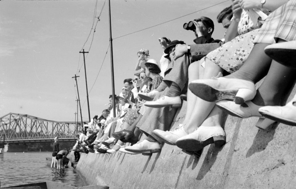Close up of legs of spectators sitting on the edge of Rivière-des-Prairies during a regatta