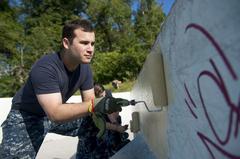 US Navy sailor painting skateboard park during Star-Spangled Spectacular community event at Carroll Park