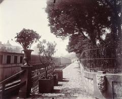 Historic black and white photograph of the south side of Vert-Galant bank near Pont des Arts in Paris, featuring urban elements like trees, a barrière, masks, a barge on the Seine River, and the dome of the Institut de France, taken in 1910 by Eugène Atget