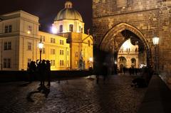 Night view of old town square architecture with illuminated church steeple and arches in Prague