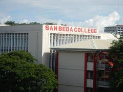 San Beda College campus buildings and surrounding Manila Light Rail Transit elevated tracks with pedestrian footbridge in Santa Cruz, Manila