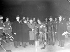 Notary Beauchesne presenting a suitcase to Detroit Red Wings goalkeeper Connie Dion on ice during a hockey game between Montreal Canadiens and Detroit Red Wings