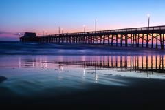 Scenic view of Newport Beach with calm water reflecting buildings and palm trees during sunset