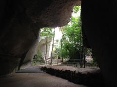 Rock-cut quarries with lush greenery and stone benches at Latomie dei Cappuccini in Siracusa, Italy
