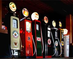 Vintage gas pumps, globes, signs and classic vehicles at Heritage Park museum during dusk