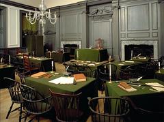 Assembly Room of Independence Hall with tables and chairs arranged in two semi-circular rows facing a central table where the Declaration of Independence and U.S. Constitution were signed