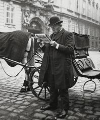 Coachman reading newspaper during a break in front of the Bohemian Chancellery at Judenplatz, Vienna