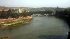 Etsch river flowing through Verona Italy with historic buildings along the riverbank under a cloudy sky