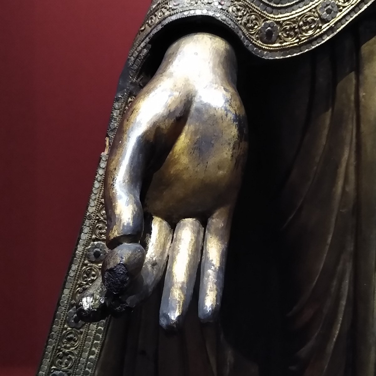 Close-up of gilded standing Buddha statue hand holding a myrobalan fruit at Chester Beatty Library Dublin
