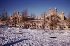 Exterior view of Matadero Madrid cultural center building with red brick walls and large arched windows under cloudy sky