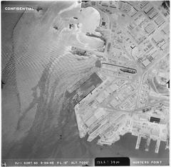 Aerial photograph of an unidentified CVL type aircraft carrier docked with several other vessels at a port seen from 7000 feet altitude