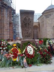 Khachkar stone monument with flowers in front of the Holy Transfiguration Cathedral in the Armenian monastery complex in Moscow
