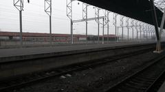 Platforms of Yerevan Railway Station in Armenia with trains and overhead electrical wires under a partly cloudy sky