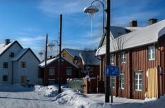 Old street covered in snow during winter in Tromsø with wooden houses and streetlamp
