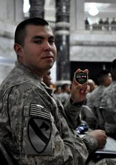 Army Pfc. Aldo Flores holding Multi National Force - Iraq Commander Gen. Raymond Odierno commemorative coin during naturalization ceremony at Al Faw Palace, Iraq